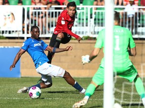Cavalry FC's José Escalante (center) will put a cross in the box in front of FC Edmonton defender Nyal Higgins at the ATCO field in Spruce Meadows on Sunday, June 26, 2022.