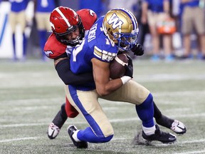 Bombers slotback Nic Demski is brought down by Stampeders linebacker Brad Cowan.