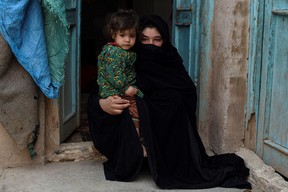 In this photo taken on Feb. 3, 2022, Aziza, who plans to sell her kidney to raise money for her family, poses with her young daughter Parwina at their house in Herat.
