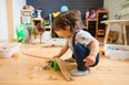 Little boys play with a wooden railroad in a stylish nursery. Home comfort.