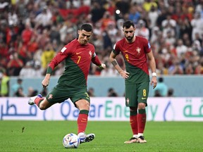 Portugal's forward #07 Cristiano Ronaldo (L) kicks the ball next to Portugal's midfielder #08 Bruno Fernandes during the Qatar 2022 World Cup round of 16 football match between Portugal and Switzerland at Lusail Stadium in Lusail, north of Doha on December 6, 2022.