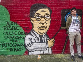Downtown Eastside street artist Trey Helten by the mural he painted in Chinatown memorializing Chinese photographer Yucho Chow.