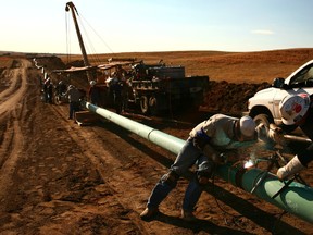 Workers install a pipeline in the United States as both oil and natural gas lines to key markets become key issue for Alberta Premier Alison Redford.     Bloomberg