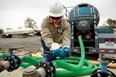 A worker connects a pump to load water into his truck at a water plant used to during the fracking process near Carthage, Texas.  JASON JANIK/BLOOMBERG NEWS