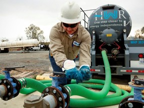 A worker connects a pump to load water into his truck at a water plant used to during the fracking process near Carthage, Texas.  JASON JANIK/BLOOMBERG NEWS