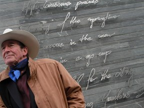 Ian Tyson stands in front of his lyrics from "Land of Shining Mountains"on a CTrain signals building wall