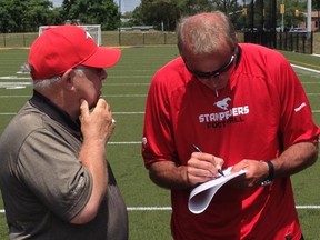 Stamps coach and GM John Hufnagel signs an autograph for a fan on Tuesday in Kingston, Ont.