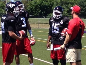 From left, quarterbacks Bo Levi Mitchell, Brad Sinopoli and Kevin Glenn listen to offensive co-ordinator Dave Dickenson during Monday's practice in Kingston.