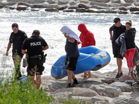 Members of the Calgary Fire Department and Calgary Police Service talk with three rafters who made it to the shore following their raft capsizing through Harvie Passage on July 2, 2012. A four rafter was swept down the Bow River and later died in hospital. (Colleen De Neve/Calgary Herald)