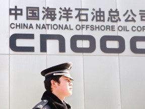 Guard walks past a sign at the offices of CNOOC, the state-owned company seeking to buy Calgary-based oil and gas producer Nexen