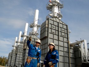 Steam generators rise behind employees at Husky Energy's Tucker oilsands project near Fort McMurray.