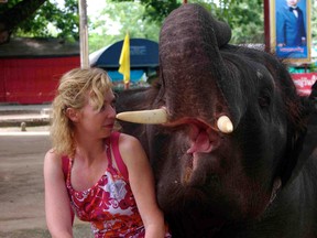 Woman sitting beside elephant