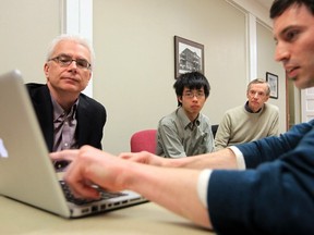 WHAT'S ON THE COMPUTER??? Benjamin Israel shows ... something ... to (L to R) Greg Miller, Jeremy Zhao and Bob Morrison at a meeting of CivicCamp. Stuart Gradon/Herald