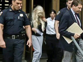 Amanda Bynes, center, wearing sweats and a blonde wig, is escorted after a Manhattan criminal court appearance on Friday May 24, 2013 in New York.