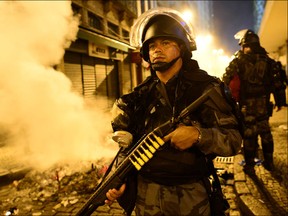 A riot police officer holds a weapon during clashes in Rio de Janeiro's downtown, on June 17, 2013. Youths clashed with police in central Rio Monday as more than 200,000 people marched in major Brazilian cities to protest the billions of dollars spent on the Confederations Cup and higher public transport costs.  CHRISTOPHE SIMON/AFP/Getty Images