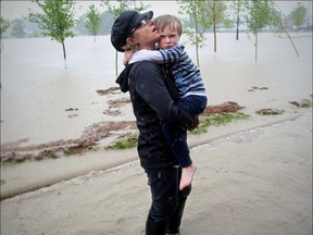 Shylow Romaniak holds her son as they wait to be placed on a combine harvester that was being used to rescue stranded people in High River, Alberta Thursday, June 20, 2013. Photo: Stuart Gradon/Calgary Herald