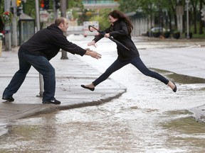 CALGARY, ALBERTA.:  JUNE 21, 2013 --  Blake Wartenbe catches his wife Desiree as she jumps over flowing water in a flooded downtown Calgary, Alberta on June 21, 2013. For City story by ? (Leah Hennel/Calgary Herald)