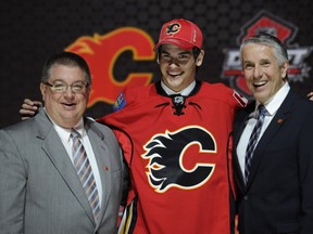 Sean Monahan, a center, stands with officials from the Calgary Flames sweater after being chosen 6th overall in the first round of the NHL hockey draft, Sunday, June 30, 2013, in Newark, N.J. (AP Photo/Bill Kostroun)