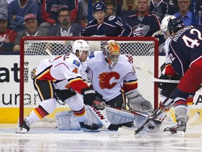 Kris Russell #4 of the Calgary Flames reaches in to knock away a loose puck from in front of Joey MacDonald #35 of the Calgary Flames as Artem Ansimov #42 of the Columbus Blue Jackets attempts to gain control of the puck during the third period on October 4, 2013 at Nationwide Arena in Columbus, Ohio. Calgary defeated Columbus 4-3.