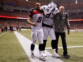 Calgary Stampeders' Micah Johnson, centre, is helped to the locker room by Jon Cornish, left, and Dr. Ian Auld after suffering an injury during first half CFL football action against the B.C. Lions in Vancouver, B.C., on Friday November 1, 2013. THE CANADIAN PRESS/Darryl Dyck