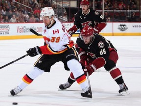 T.J. Galiardi #39 of the Calgary Flames skates with the puck ahead of Mikkel Boedker #89 of the Phoenix Coyotes during the second period of the NHL game at Jobing.com Arena on January 4, 2014 in Glendale, Arizona.