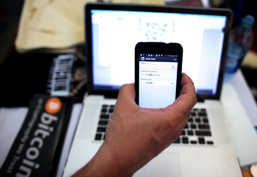 Using a phone to transfer Bitcoins to buys a tee-shirt. (Photo by Joe Raedle/Getty Images)