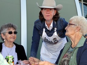 An emotional Premier Alison Redford talks with Margaret Braid, left, and Bert Ager at her Stampede breakfast in Aldersyde on July 7, 2013. She moved the event so people affected by the floods could take part. Lorraine Hjalte, Calgary Herald.