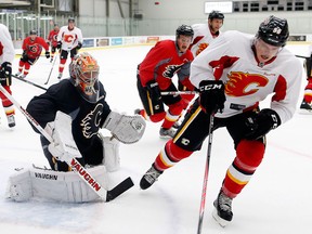 Flames goalie Joey MacDonald follows the puck as Tyler Wotherspoon, skates past with it during training camp in Calgary Sept. 12, 2013.