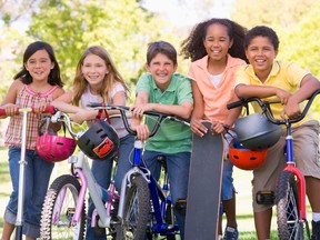 Five young friends with bicycles scooters and skateboard outdoor