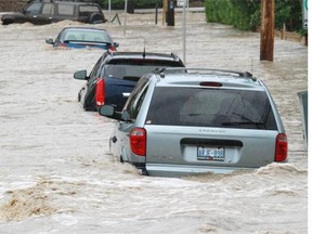 Water rushes down a street in the Mission area of Calgary on Friday morning June 21, 2013.