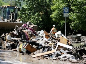 Workers clean up in Bowness, a few days after the June flood. Reader says those dealing with flood devastation don't feel so rich.