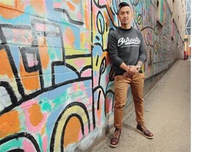 Andy Nguyen of 6streets in his favourite graffiti-filled alley in Calgary. He is wearing a 6streets Script crewneck sweatshirt, Topman dark khaki pants, Red Wing round-toe boots, Gold Nixon watch and 6streets feather bracelet.