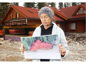 Barb Teghtmeyer holds a photo of the June 2013 Elbow River flood waters as that overwhelmed her home and business, the historic Bragg Creek Trading Post, on Sunday May 19, 2014.