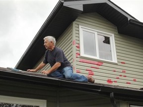 Les Bruce was busy taping up the holes in his siding after a large storm left homeowners in Airdrie with a big clean up job.