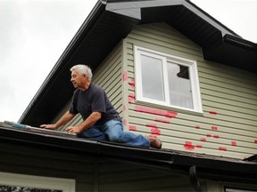 Les Bruce tapes holes in his siding a day after a large hailstorm hit Airdrie on Aug. 7. The cost of the storm pushed total insurance payouts from natural catastrophes to $4 billion over the past three years.
