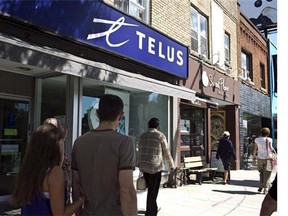 Pedestrians walk by a Telus store on Bloor Street West in Toronto on August 15, 2013. Telus Corp. says it will spend $500 million in Ontario in 2014