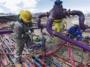 Workers tend to a well head during a hydraulic fracturing operation at an Encana gas well outside Rifle, in western Colorado.