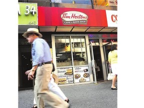 People walk past a Tim Hortons cafe in Manhattan on Monday as news gets out that American fast food giant Burger King wants to buy the Canadian coffee shop chain.