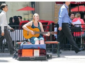 A busker plays her guitar during lunch hour on Stephen Avenue in downtown Calgary.