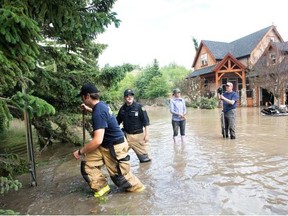 Calgary firefighters check on homes last June as residents and volunteers were in flood cleanup mode in the community of Bowness.