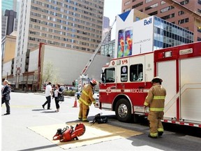 Calgary firefighters inspect the east side of a building at the corner of 7th Street and 6th Avenue S.W. after bricks fell and the wall bowed on Tuesday.