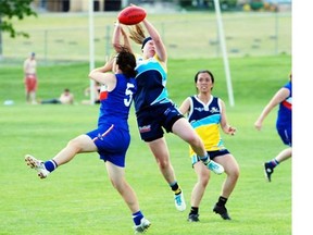 Caity Kidd (jumping) and Edmonton Player Lisa Annicchiarico battle in Aussie rules football.