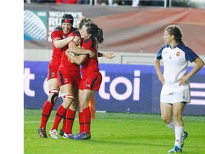 Calgary's Maria Samson, left, celebrates Canada's first try of Wednesday's women's rugby World Cup semifinal, with teammates, including scorer Elissa Alarie, right. Canada hung on to beat France 18-16 to advance to Sunday's final against England. (AP Photo/Remy de la Mauviniere)