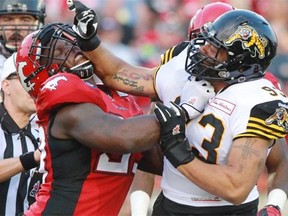 Calgary Stampeders defensive lineman Micah Johnson and Hamilton Tiger Cats defensive tackle Terrence Moore tangle in the first quarter of their CFL game at McMahon Stadium on Friday.