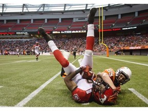 Calgary Stampeders' Fred Bennett, left, intercepts a pass intended for B.C. Lions' Whitman Tomusiak during the second half of a pre-season CFL football game in Vancouver, B.C., on Friday June 20, 2014. THE CANADIAN PRESS/Darryl Dyck