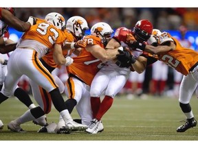 Calgary Stampeders’ Matt Walter, centre, is tackled by a gaggle of B.C. Lions in Vancouver on Friday.