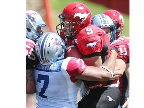 Calgary Stampeders running back Jon Cornish gets crunched by a posse of Montreal Alouettes in the teams’ CFL season opener last month. He was later concussed by a dangerous Kyries Hebert hit and has just now been cleared to practise.