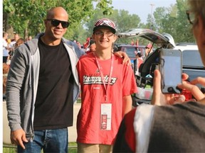 Calgary Stampeders running back Jon Cornish poses for a picture with fan Maya Barnes, 7, before the Calgary Stampeders vs. Hamilton Tiger Cats game at McMahon Stadium on Friday.