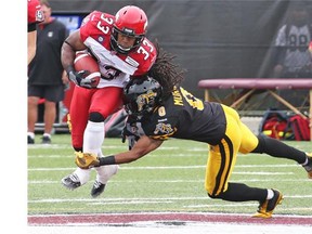 Calgary Stampeders running back Hugh Charles chugs up the field as Hamilton’s Rico Murray makes the tackle during Saturday’s game in the Steel City.