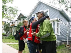 Christina Ryan, Calgary Herald Calgary, Alberta: July 06, 2013 -- Mike Bradfield, a resident in Sunnyside Community, receives a hug from Red Cross workers who helped him out with walmart cards to help recover after a flash flood left residents with more flood damage in Calgary on July 6, 2013. Photo by Christina Ryan, Calgary Herald (For City section story by TBA)